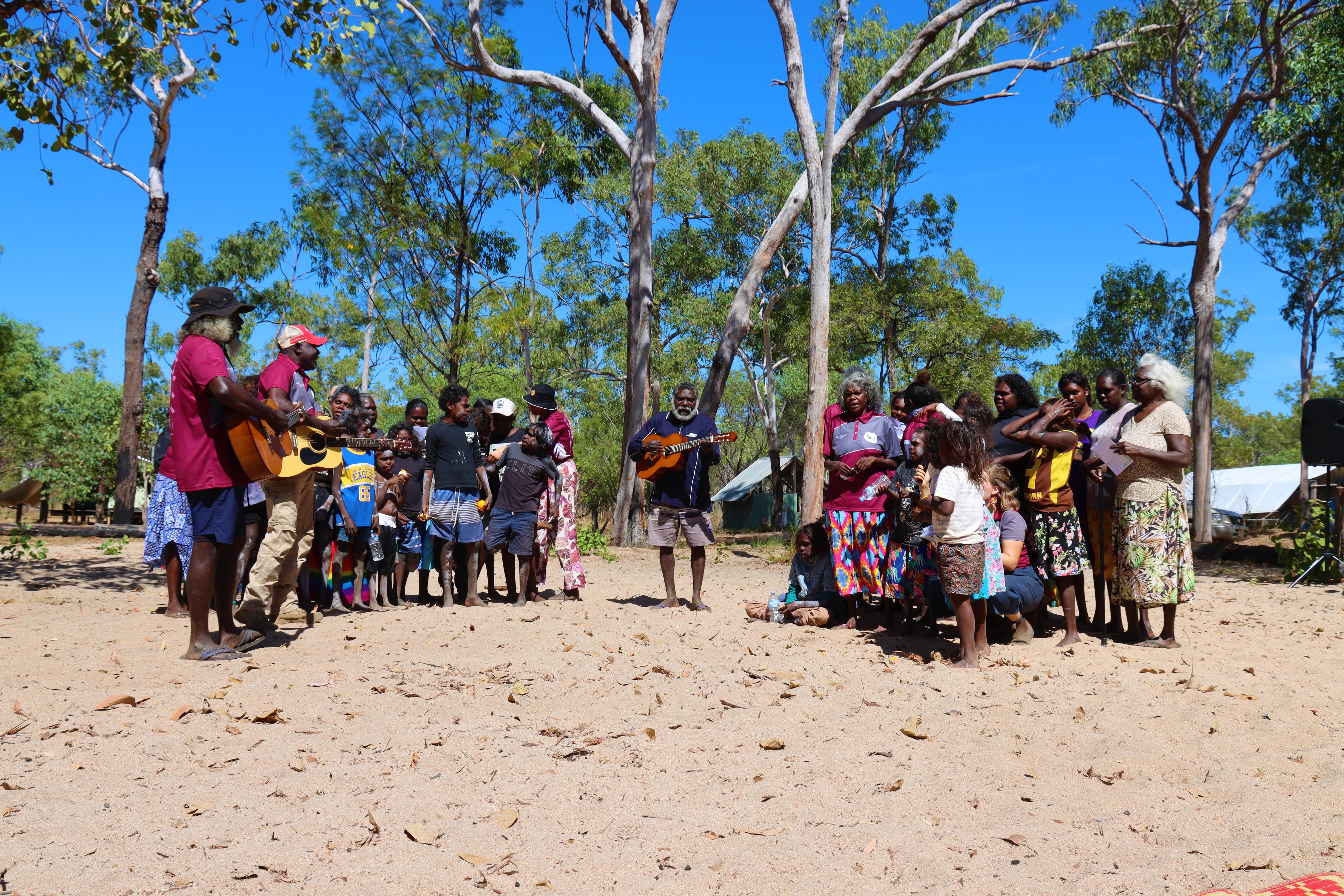 A group sing while standing on sand.