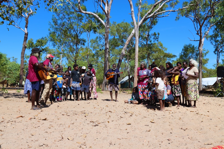 A group sing while standing on sand.