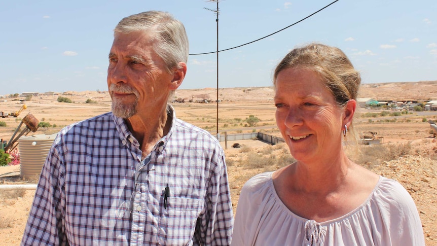 Man and woman stand on a hill overlooking Coober Pedy.