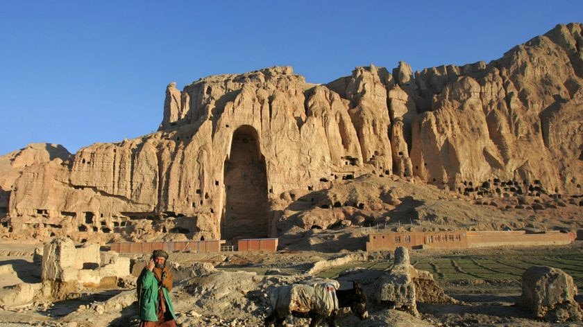 An Afghan man walks past the remains of the Giant Buddha destroyed by the Taliban in March 2001 in c