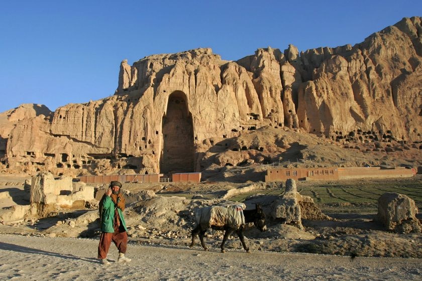 Un uomo afghano passa davanti ai resti di una gigantesca statua del Buddha distrutta dai talebani nel marzo 2001 a C