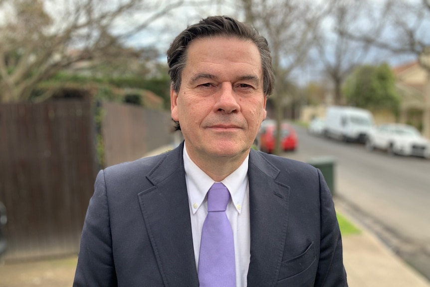 A man wearing a suit and purple tie.