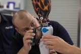 A man bending over looking at a prosthetic leg on a machine