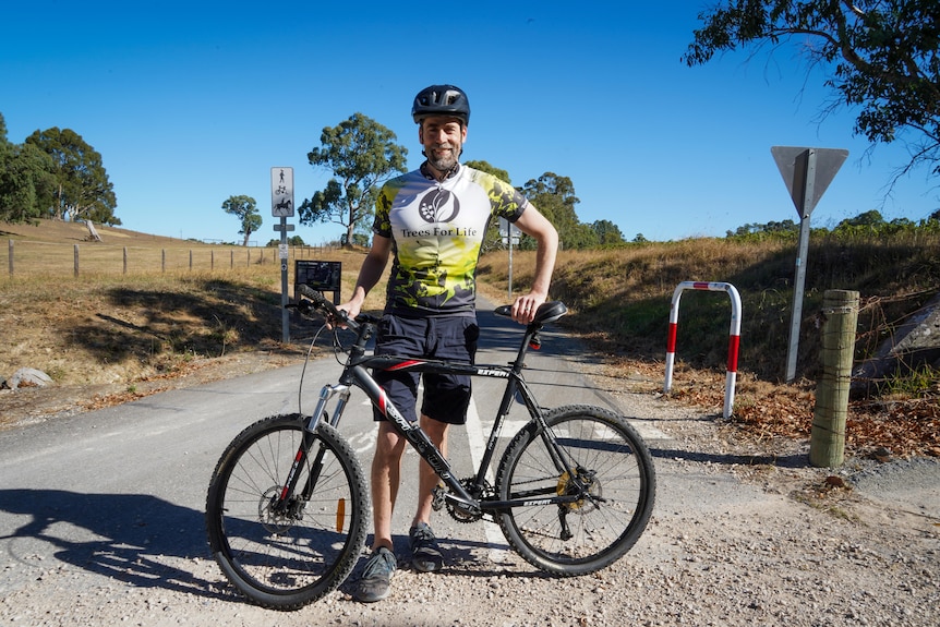 Nathan Daniells stands holding mountain bike