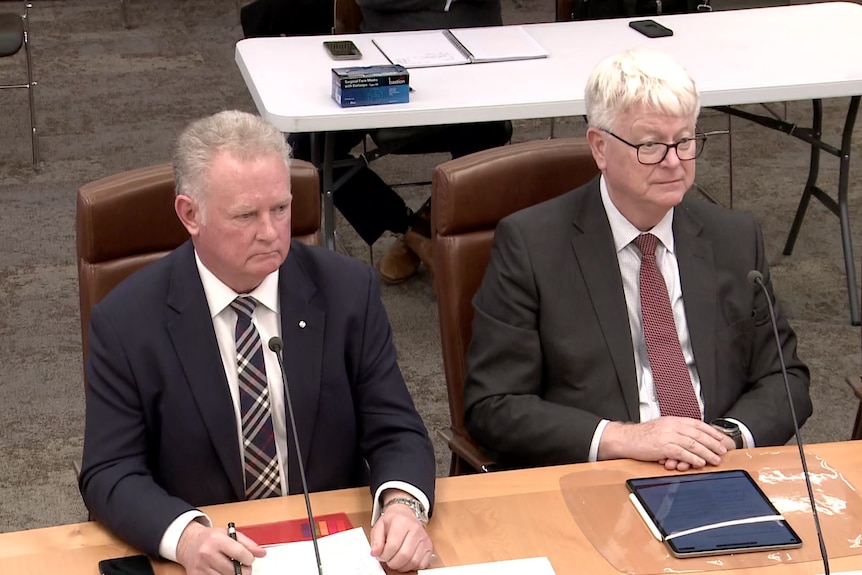 Michael Grainger and Bernard Dwyer sit at a table with microphones in front of each of them