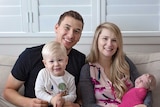 Amy Steenbergen, her partner and their two young children sit on a couch.