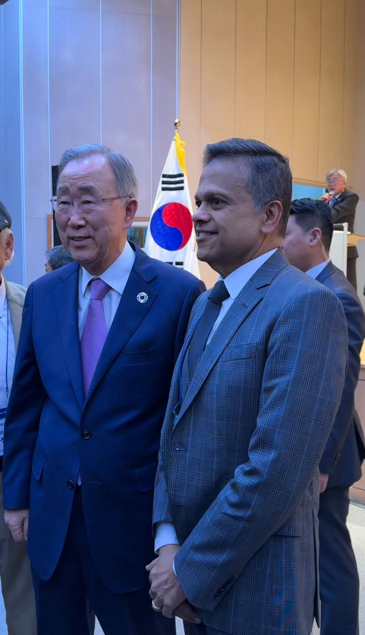 Dois homens em ternos executivos ficam ombro a ombro, sorrindo.