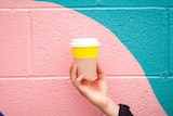 Woman holding coffee cup in front of wall