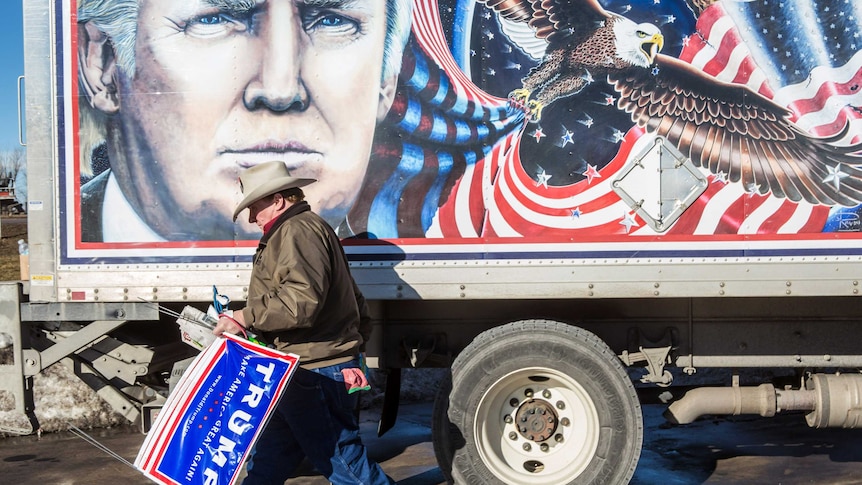 A supporter of Donald Trump stands next to a truck featuring a painting of the presidential candidate in Des Moines, Iowa.