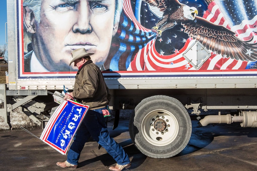 A supporter of Donald Trump stands next to a truck featuring a painting of the presidential candidate in Des Moines, Iowa.