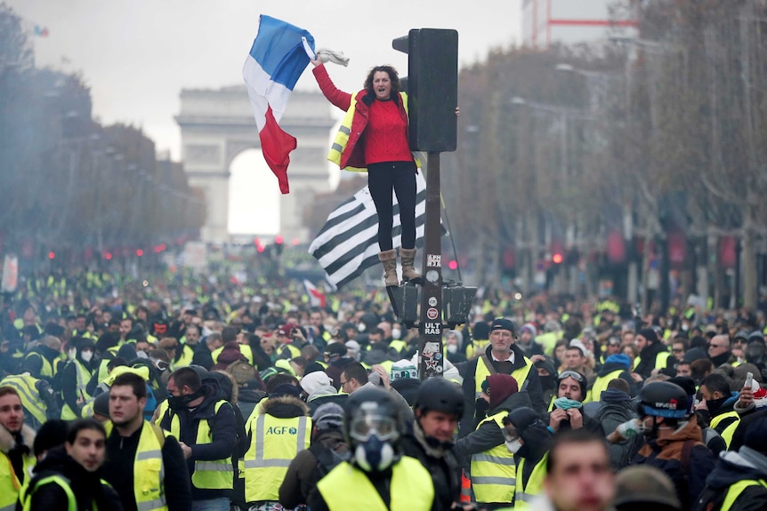 A protester wearing yellow vest stands on the red light on the Champs-Elysee in Paris.