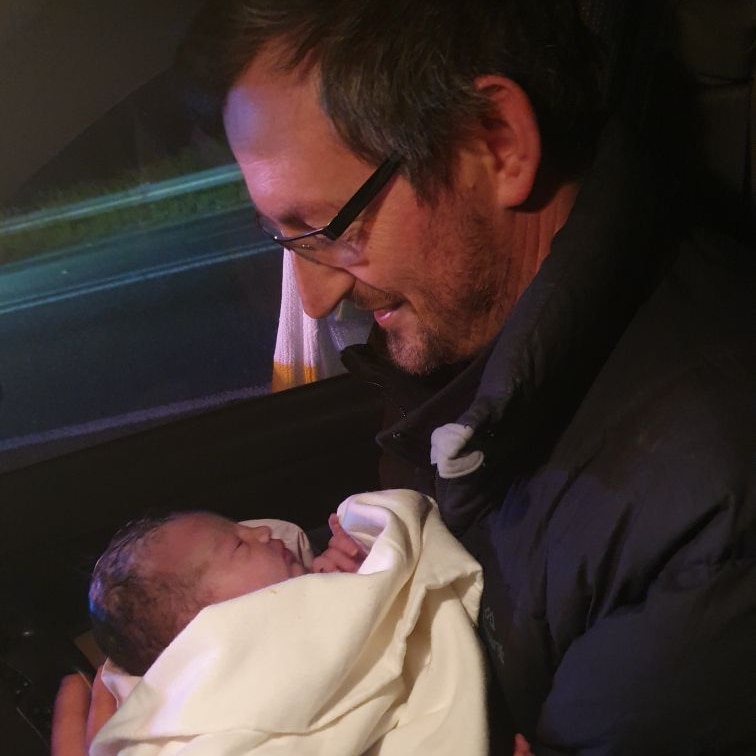 a man in a car smiles down at his newborn son