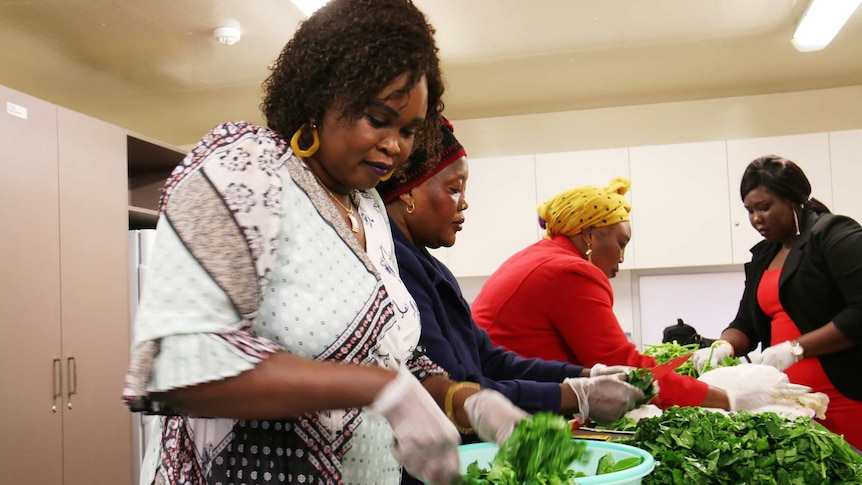 Monica Majak (left) and volunteers from the South Sudanese Mothers Coalition prepare lettuce for kombo, a traditional dish.