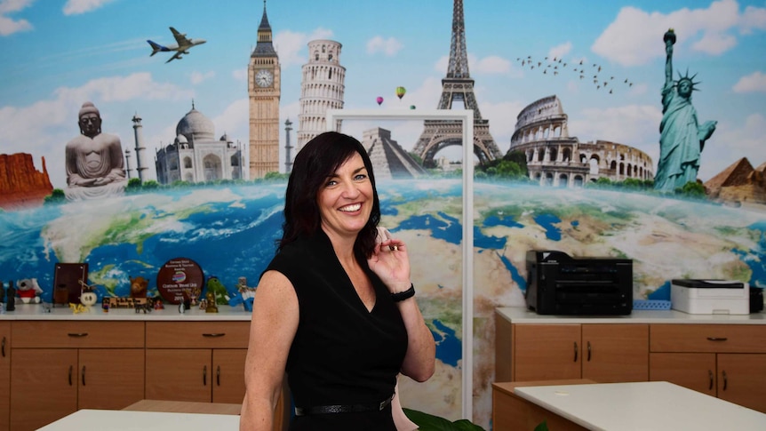 Woman, smiling, standing in front of a mural