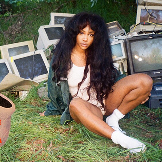 SZA lays on a grassy hill in front of dozens of broken desktop computers.