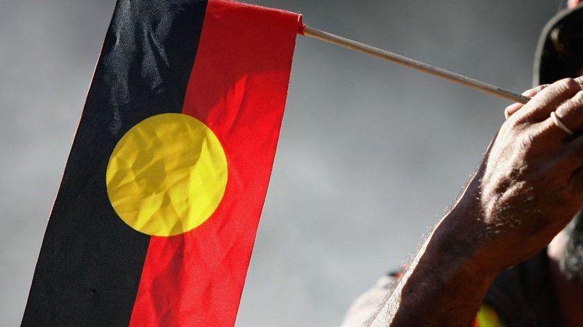 An elder holds an Aboriginal flag