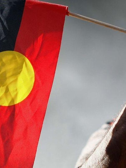 An elder holds an Aboriginal flag