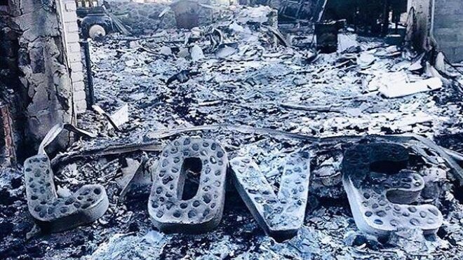 Large letters spelling out 'love' are shown sitting on the ashes of a home and its contents.