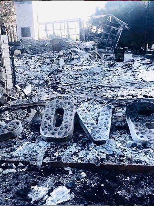 Large letters spelling out 'love' are shown sitting on the ashes of a home and its contents.