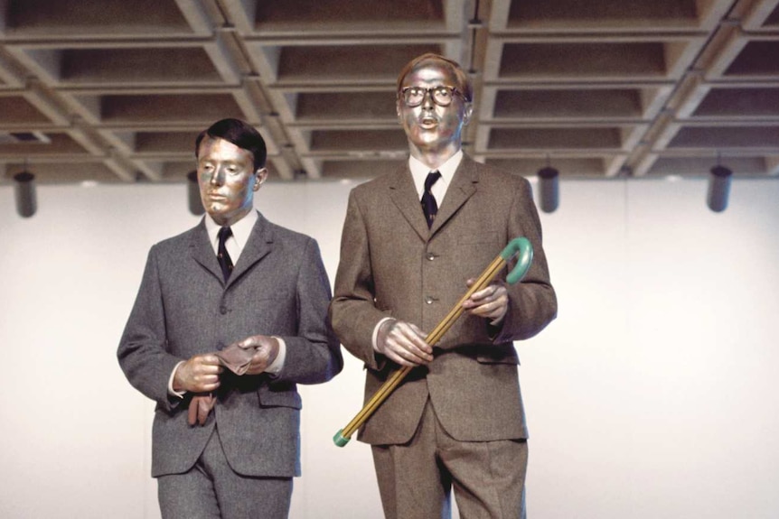 Gilbert and George painted in metallic paint perform The Singing Sculpture to an art gallery audience in 1973