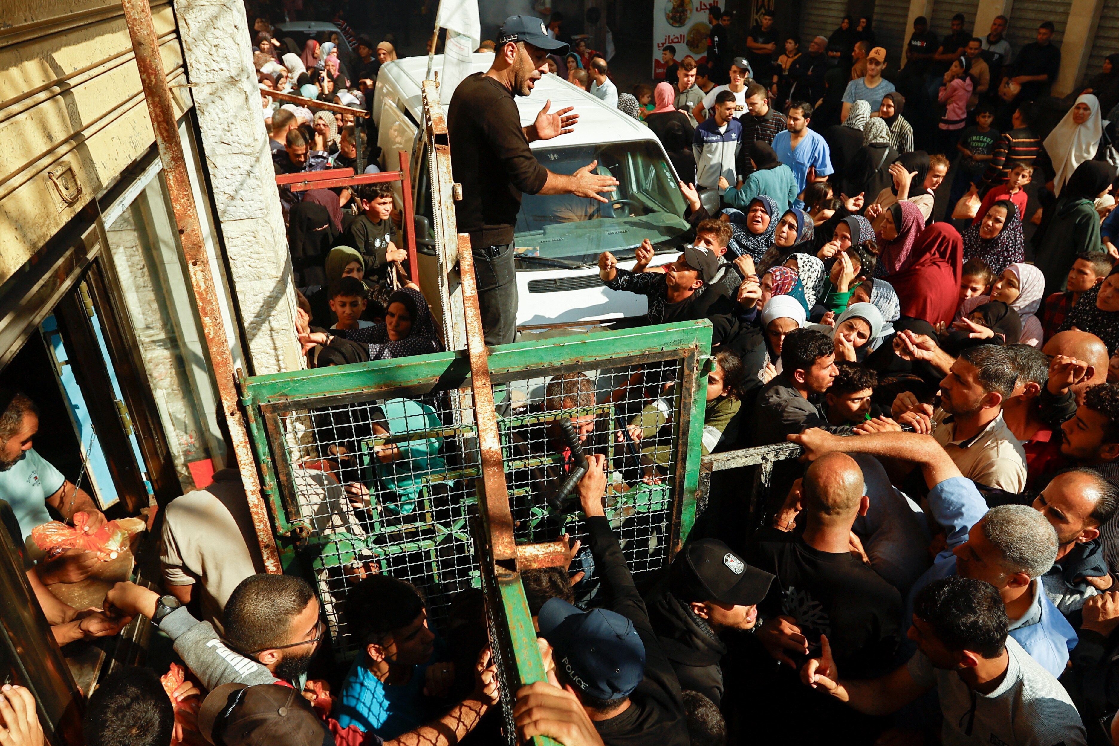 people crowd on the street outside of a shop with a rotating gate