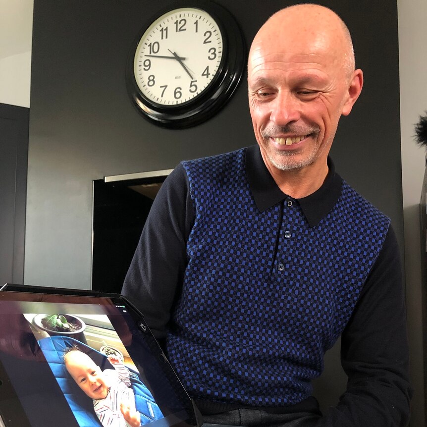 Man looking at a tablet that shows a picture of a baby.