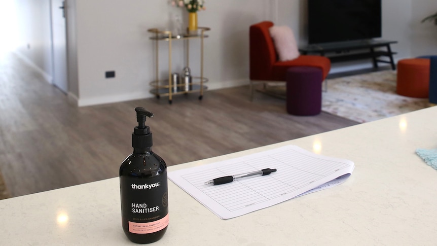 A pump pack of hand sanitiser sits on a benchtop inside the living area of a house.