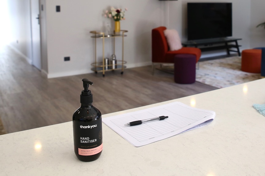 A pump pack of hand sanitiser sits on a benchtop inside the living area of a house.