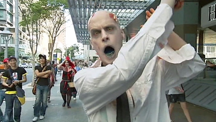 A man dressed as a zombie in a business shirt lurches through Brisbane