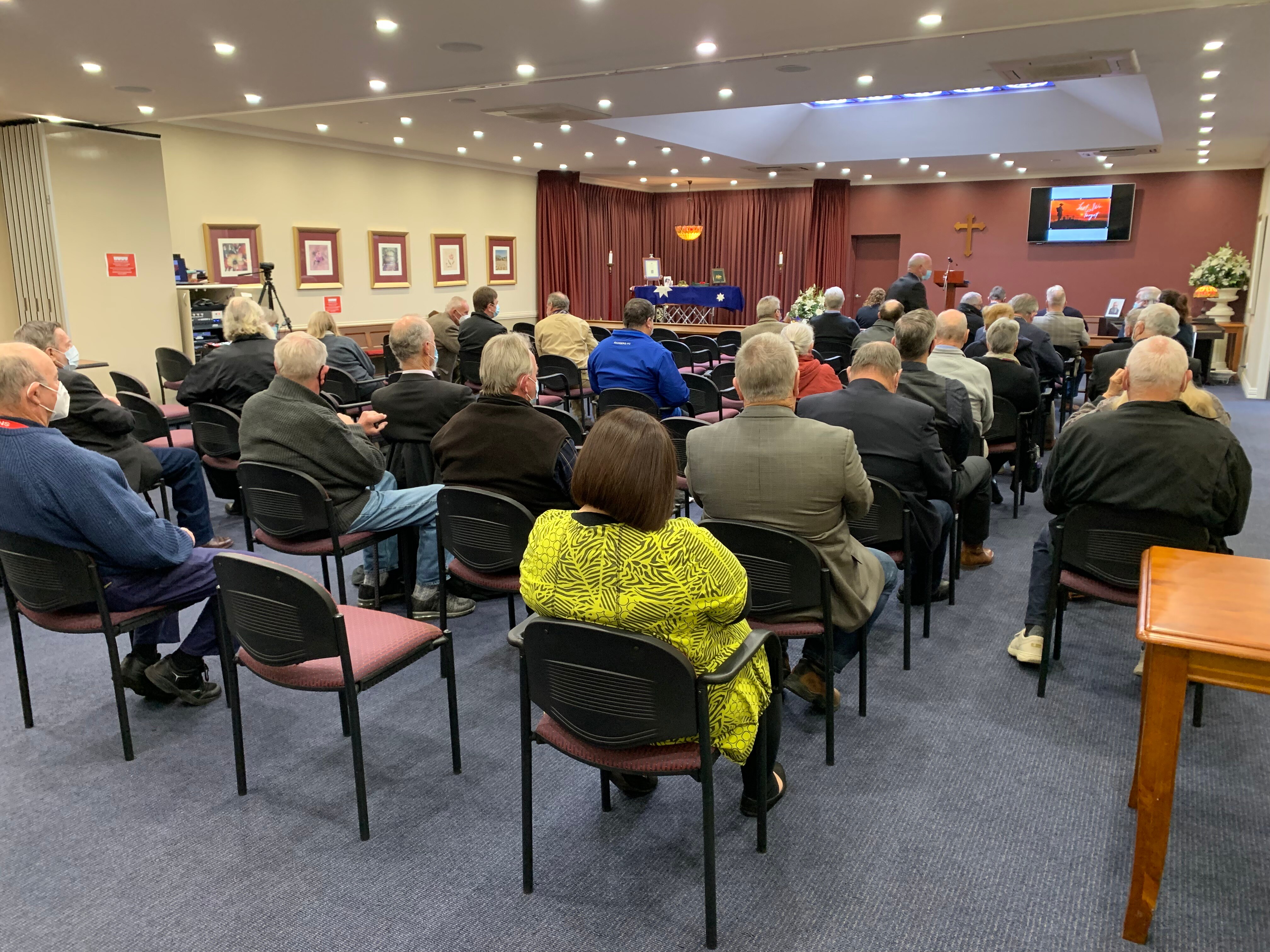 People sitting on chairs in a hall for a funeral service