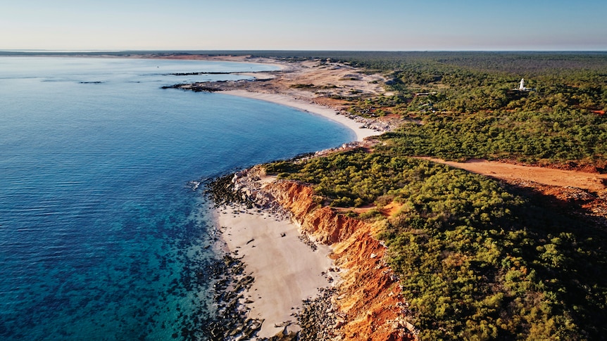 Image of the coastline that shows bright blue sea, white beaches and dense green bushland.