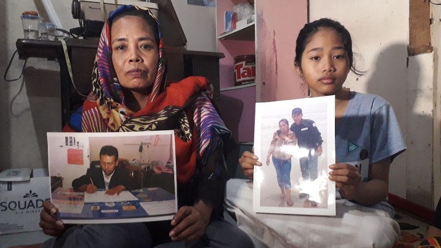 Rohani Baso and daughter hold family photos of Imam Nurokhim who died in the oil spill
