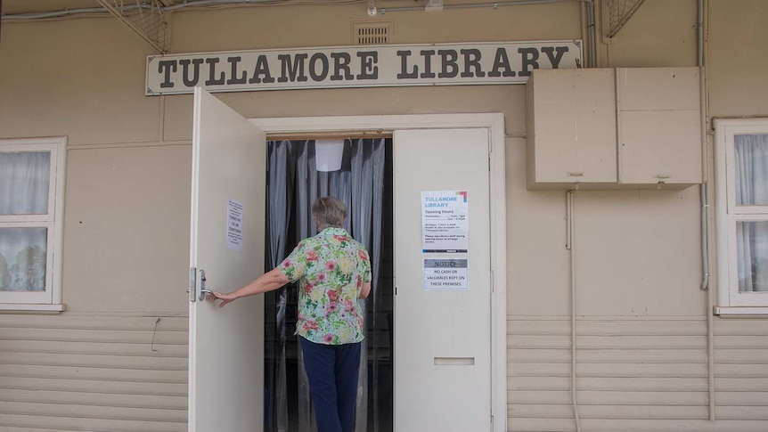 A woman walking through a door with the sign over the door saying Tullamore Library