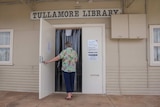 A woman walking through a door with the sign over the door saying Tullamore Library