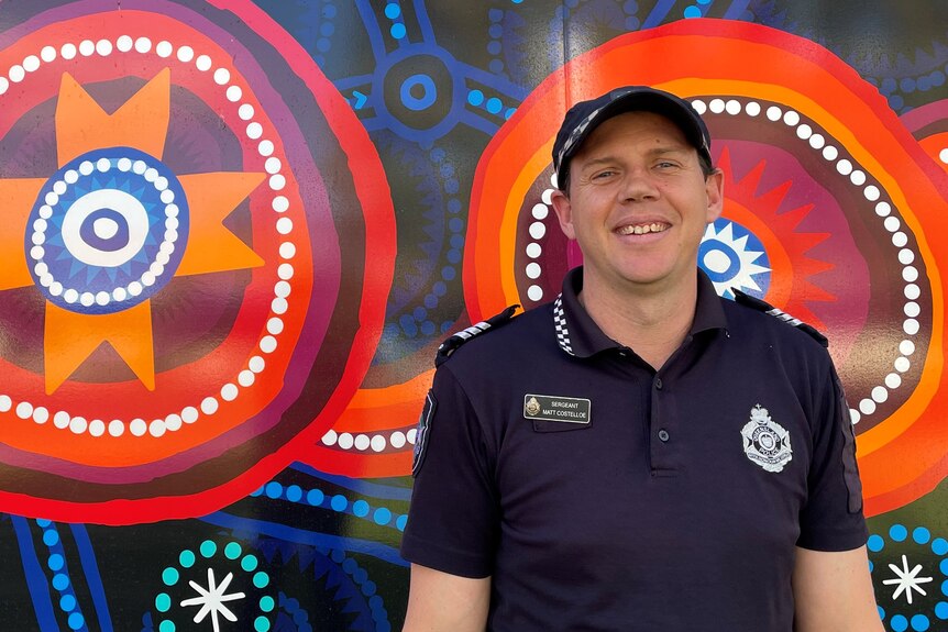 Police officer smiling with indigenous art in the background