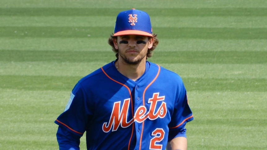 A man wearing a blue baseball cap and shirt on a grass field.