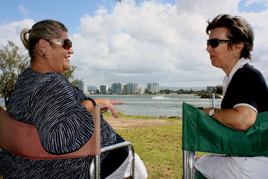 Two women sitting in camp chairs facing each other, overlooking water at The Spit on the Gold Coast.