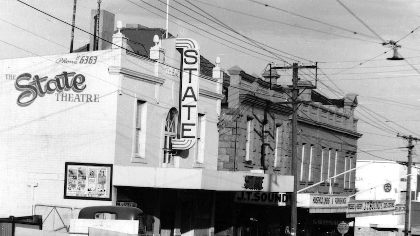 A historic photo of the State Theatre building in North Hobart with a vintage truck and cars parked out front