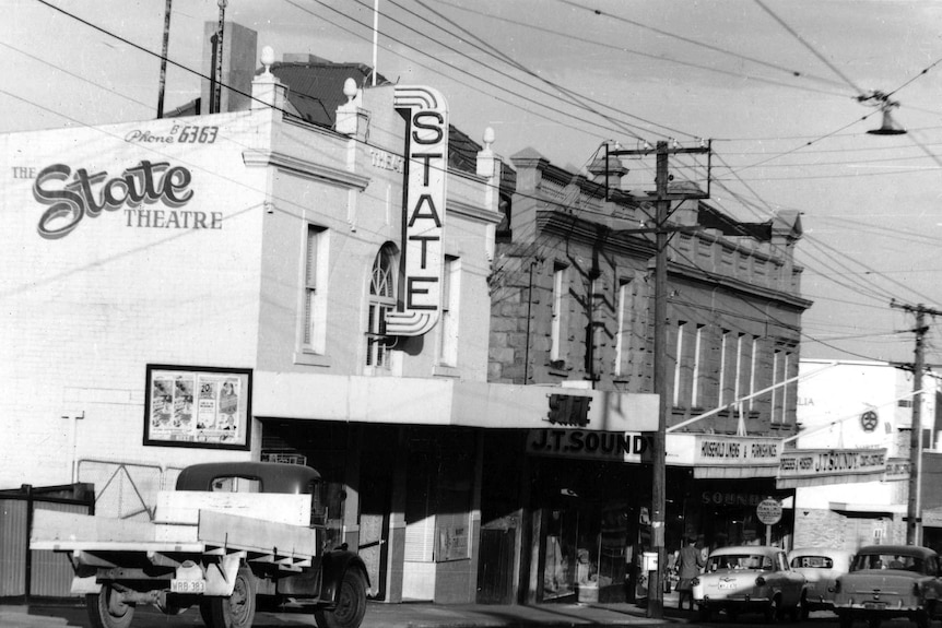 A historic photo of the State Theatre building in North Hobart with a vintage truck and cars parked out front