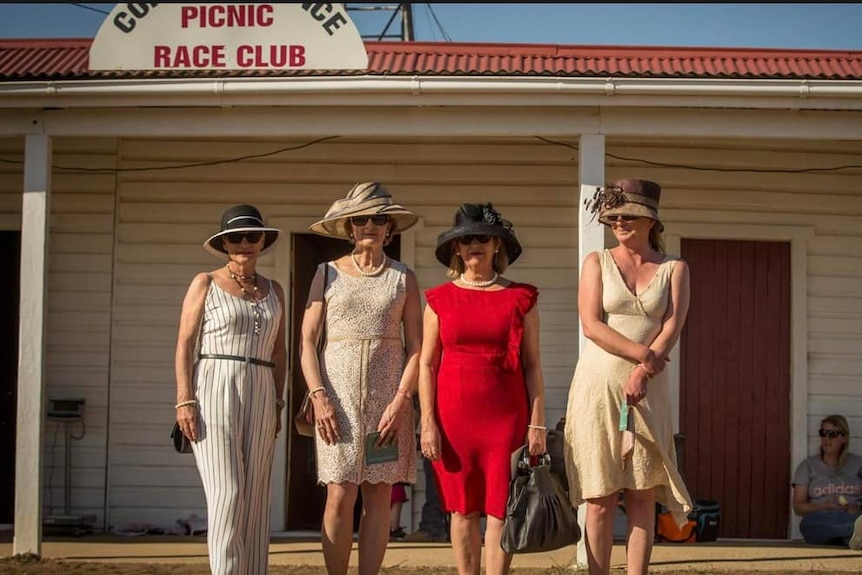 Women line up in their best fashion in front of the club house