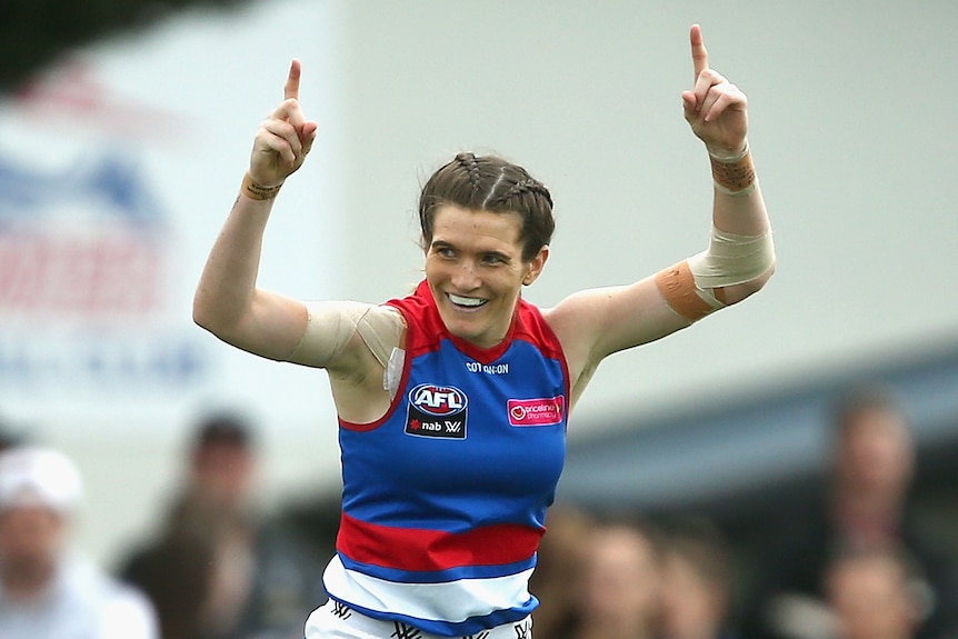 A Western Bulldogs AFLW player jumps in the air as she celebrates a goal during the 2020 season.