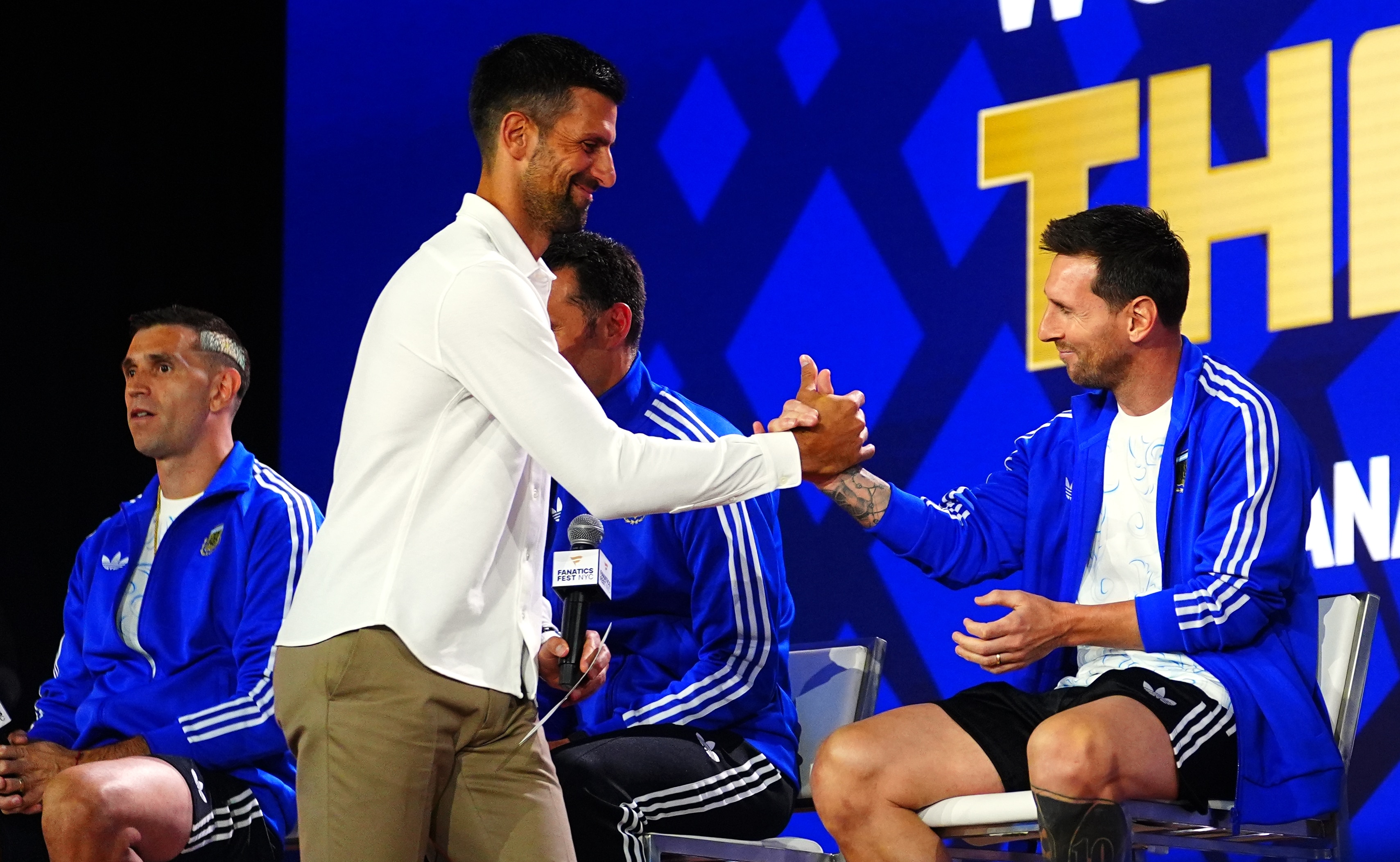 Novak Djokovic greets Lionel Messi with a hand slap