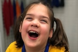 Young girl with brown hair laughs.
