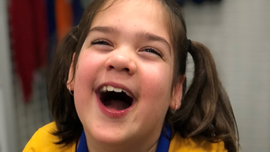 Young girl with brown hair laughs.