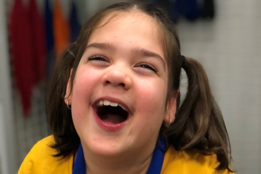 Young girl with brown hair laughs.