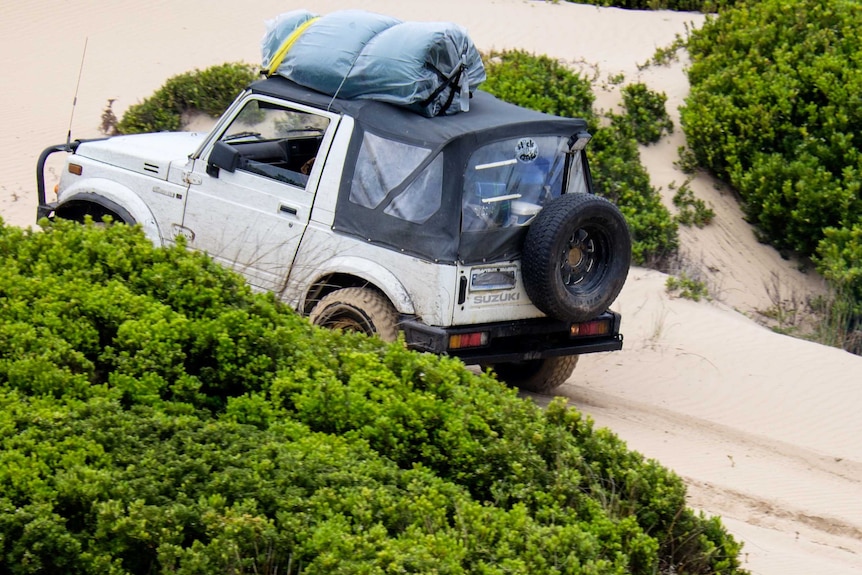 A car drives up a sand dune on Tasmania's west coast.