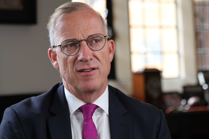 Michael Spence wears a suit with a pink tie