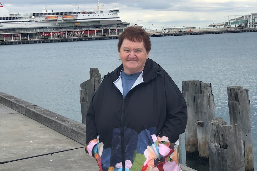 A woman in a parka smiles on a hharf