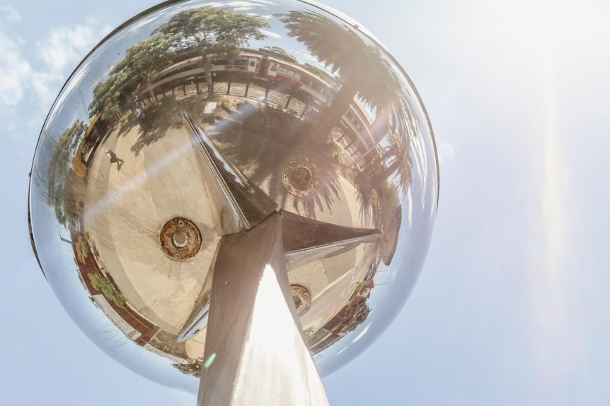 A glass sphere shows the reflection of a concrete streetscape 