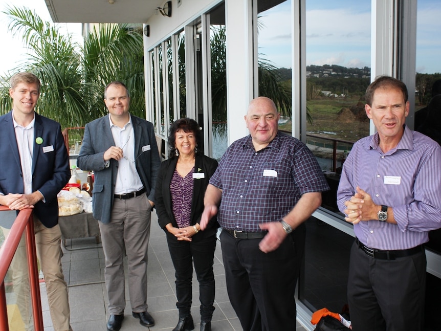 Five candidates, four men and one woman, stand on a building balcony smiling.